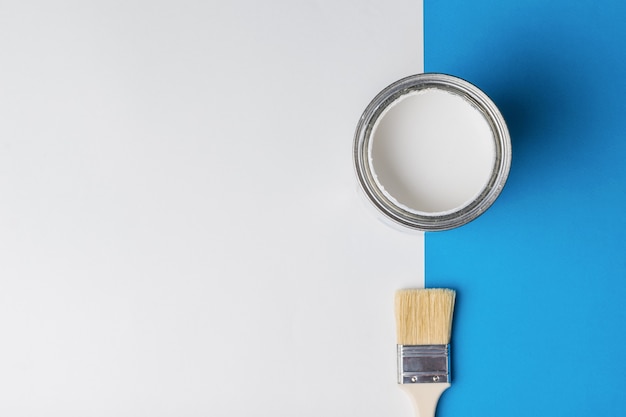 Photo brush and jar with open white paint on a blue and white background. execution of painting works.