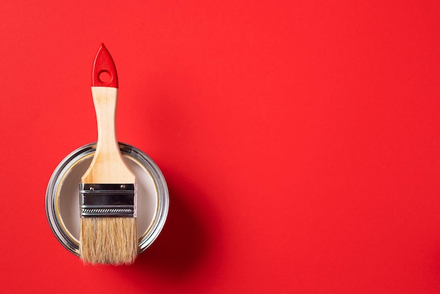 brush and open paint can on trendy red background top view copy space appartment renovation repair building and home design concept