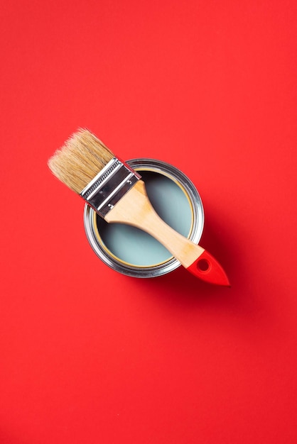 Brush and open paint can on trendy red background Top view copy space Appartment renovation repair building and home design concept