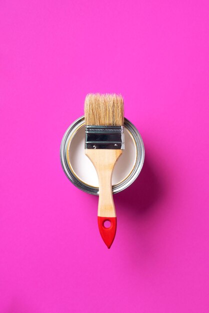 Brush and open paint can with on trendy yellow background Top view copy space Appartment renovation repair building and home design concept