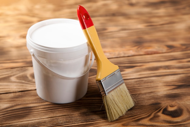 Brush on the paint bowl on the wooden table
