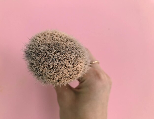 Brush in powder on a pink background brush in hand of a makeup artist Mineral and matte beige