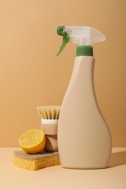 Brush sponge lemon and bottle of detergent on beige background