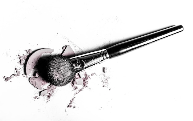 brush with crushed eyeshadow and powder closeup isolated on white background
