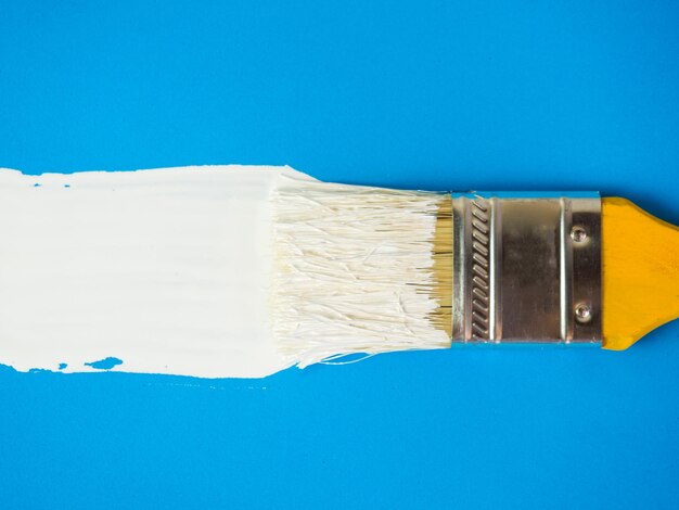 Brush with white paint draws space for text on blue background