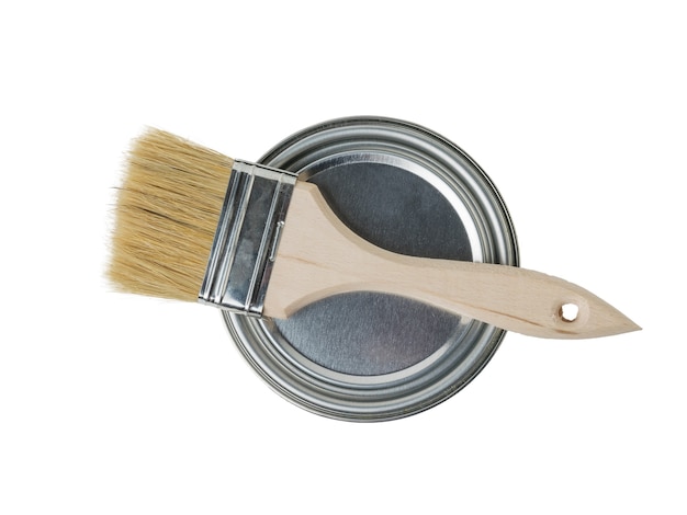 a brush with a wooden handle on a closed iron can of paint. materials for painting.