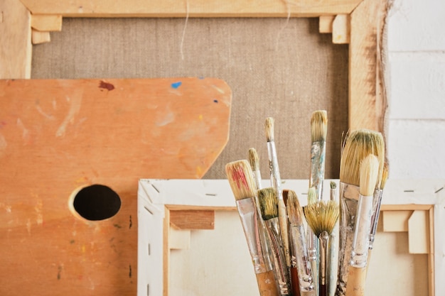 Brushes, canvases and palette against the wall