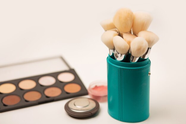 Brushes kit for face makeup in a case, contouring palette and pressed powder on a grey background