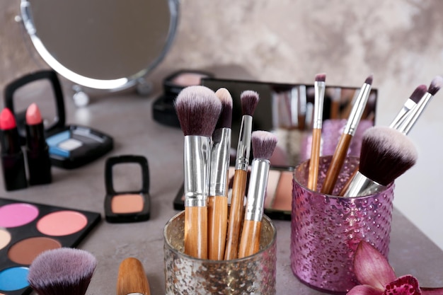 Brushes of professional makeup artist with decorative cosmetics grey table