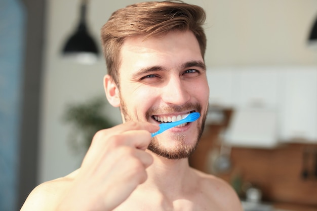 Brushing teeth in the morning. Handsome young beard man brushing his teeth and smiling.