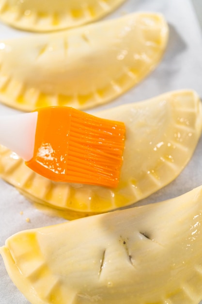 Brushing uncooked empanadas with blueberries with egg wash