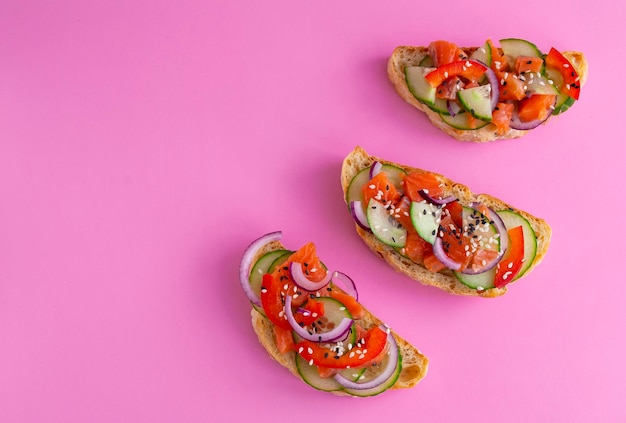 Brusketta op een roze achtergrond Zalmkomkommer paprika en sesamzaadjes op geroosterd brood