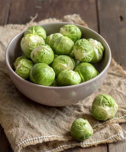 Brussels sprouts in a bowl on wooden table close up