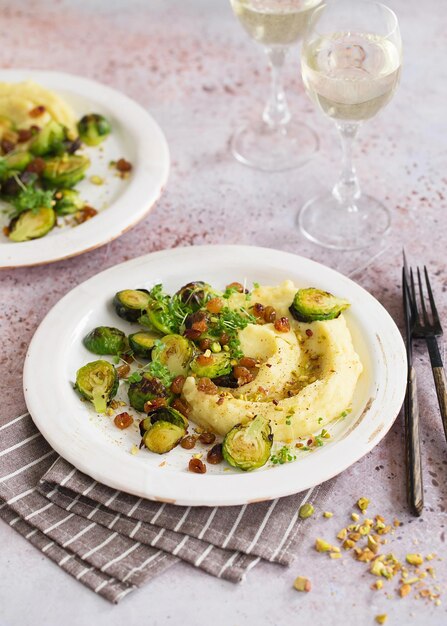 Brussels sprouts with pistachios, raisins and skordalia (mashed\
potatoes). healthy meal preparation. plant-based dishes. green\
living. vegan recipe. food styling. vegetarian cuisine. healthy\
eating