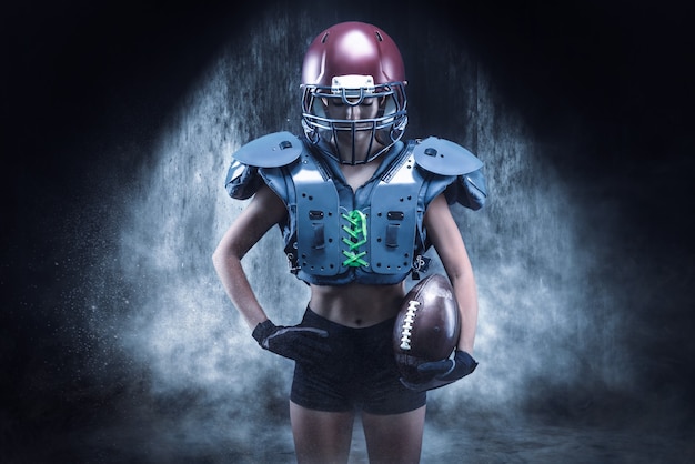 Brutaal portret van een meisje in het uniform van een American football-teamspeler. Apparatuur reclame. Sportconcept. Schoudervullingen. Gemengde media