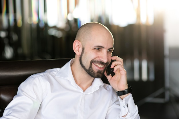 A brutal bald man talking on the phone.