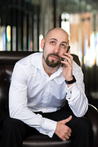 A brutal bald man talking on the phone