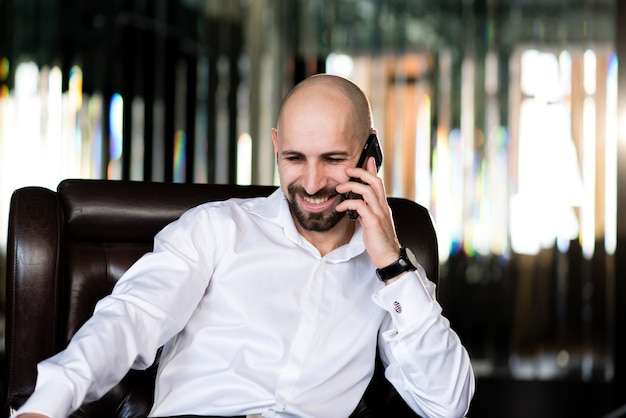 A brutal bald man talking on the phone.