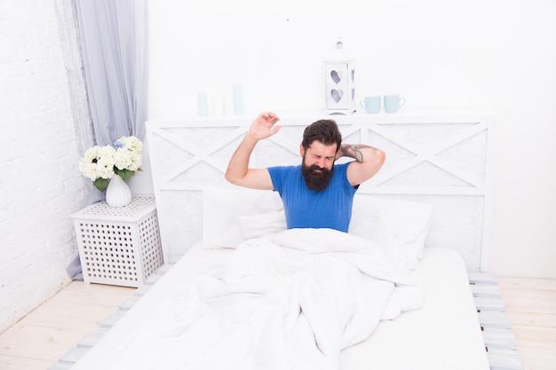 잔인한 수염 난 남자는 아침 일찍 침대에 누워 있는 동안 두통이 있습니다.
