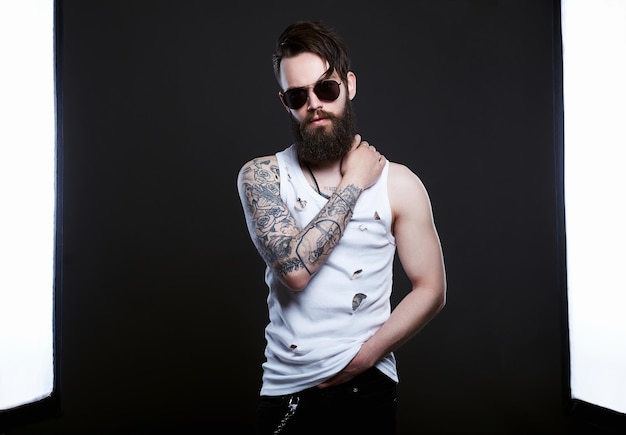 Brutal bearded hipster boy in glasses and vintage torn dirty shirt