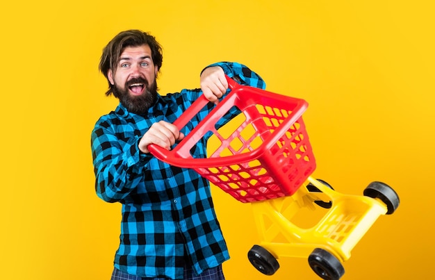 Brutal bearded male with stylish look carry shopping trolley, cyber monday.