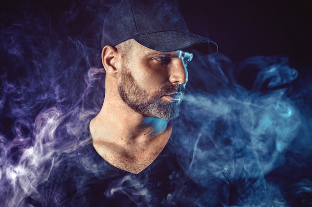 Photo brutal bearded man vaping and releases a cloud of vapor