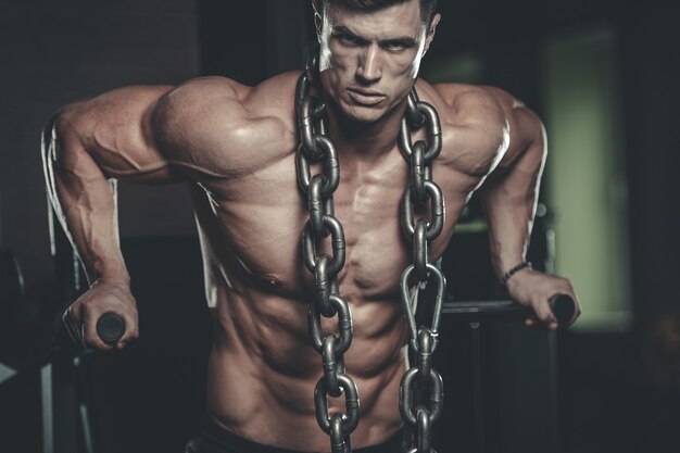 Brutal bodybuilder working out in gym with chain
