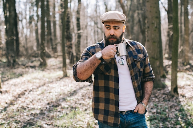 Brutal confident man with coffee in woods