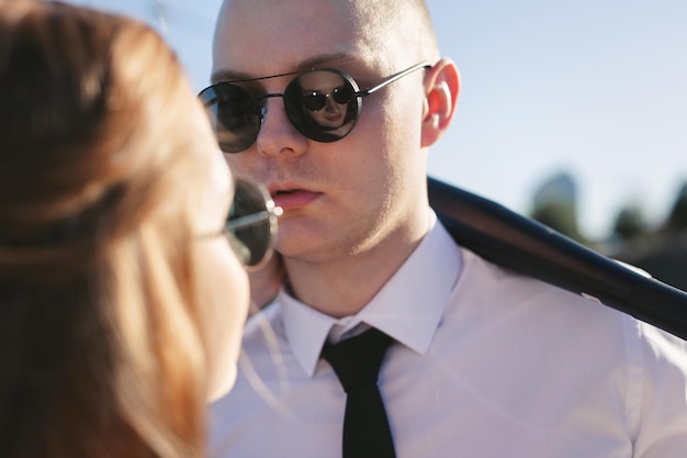 Brutal couple the bride and groom wearing black glasses near the car on the road