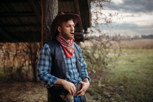 Photo brutal cowboy smokes a cigar, wild west culture