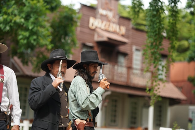 Brutal cowboy with revolver gunfight on ranch rural background