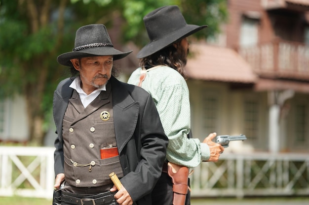Brutal cowboy with revolver gunfight on ranch rural background