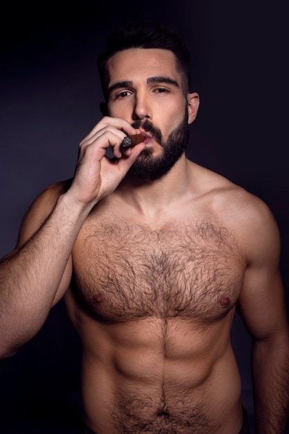 Photo brutal handsome bearded man with naked torso, smoking a cigarette