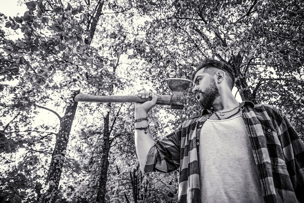 Brutal lumberjack bearded man in woods on a background of trees Black and white