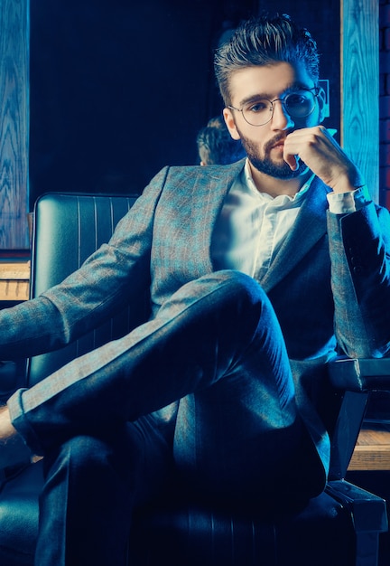 Photo brutal man in elegant suit and glasses in barbershop