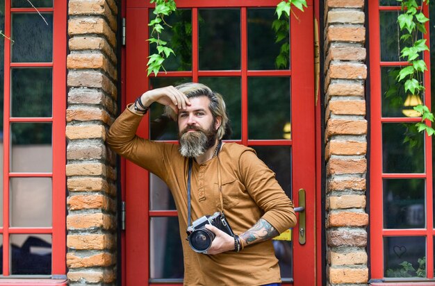Photo brutal man with retro camera creative career creative photographer urban background irish architecture style photography business professional photographer use vintage camera photo shooting