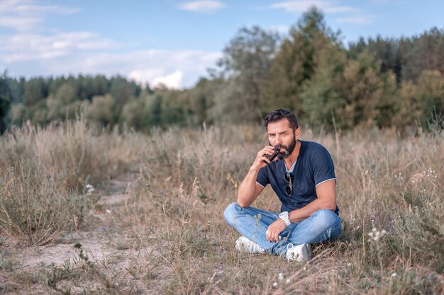 Brutal vape man is resting in the fresh air and vaping and letting off steam from an ecigarette Nontobacco smoking