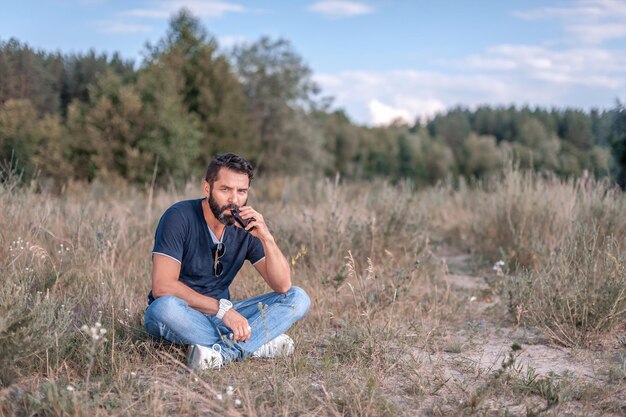 Photo brutal vape man is resting in the fresh air and vaping and letting off steam from an ecigarette nontobacco smoking