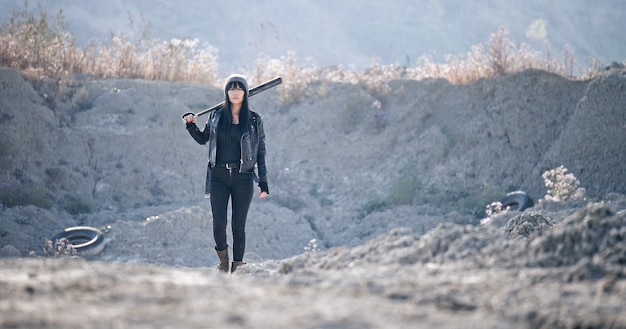 A brutal woman walks with a baseball bat through the wasteland.