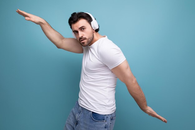 Brutale brunette man in een wit t-shirt luistert naar muziek op een koptelefoon