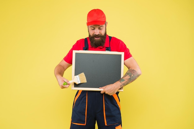 Brutale hipster ambachtsman advertentie kopie ruimte professionele reparateur gezocht bouwer man verf op blackboard bebaarde werknemer met schilderborstel bouwvakker klaar om te werken