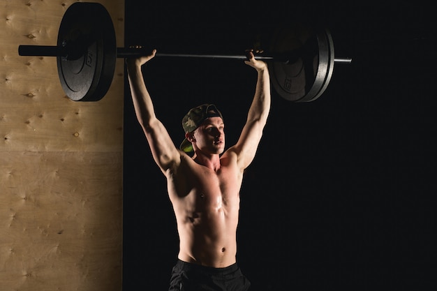 Brutale spiermens met baardtrein met barbell opgeheven lucht in gymnastiek