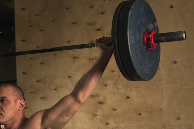 Brutale spiermens met baardtrein met barbell opgeheven lucht in gymnastiek