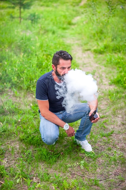 Brutalvape man die een elektronische sigaret rookt in een boskap. De nieuwe technologie sigaret.