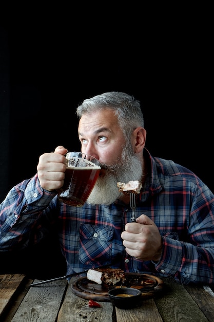 Brute volwassen man met grijs haar, gek op mosterdsteak en bier, vakantie, festival, Oktoberfest of St. Patrick's Day