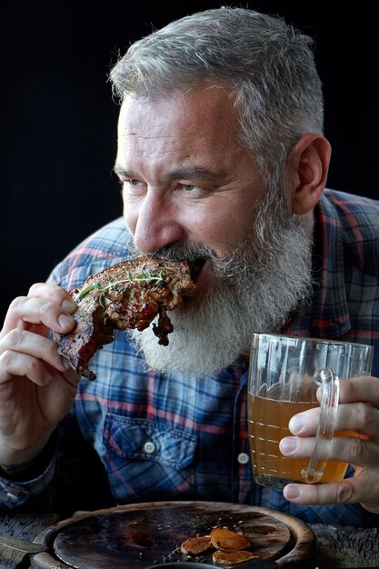 Foto brute volwassen man met grijs haar, gek op mosterdsteak en bier, vakantie, festival, oktoberfest of st. patrick's day