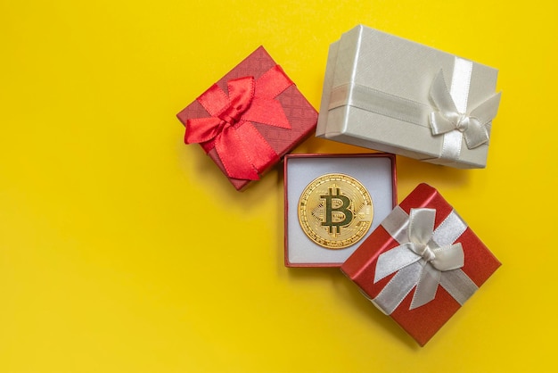 BTC-cadeau. Bitcoin munt in een rode geschenkdoos op een gele achtergrond. Ansichtkaart om af te drukken, banner met plaats voor tekst.
