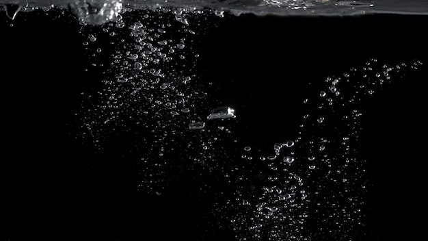 Bubbels onder water spatten en zweven en zwarte kleur achtergrond die carbonaat vertegenwoordigen