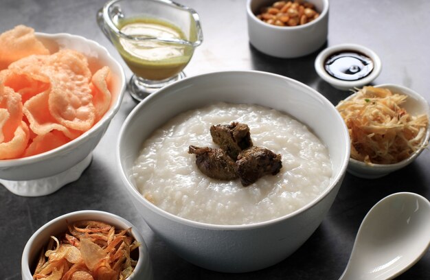 Bubur Ayam of Indonesische rijstepap met geraspte kip. Geserveerd met Kerukpuk (Cracker), Sojasaus, Gebakken Sojaboon en Sambal