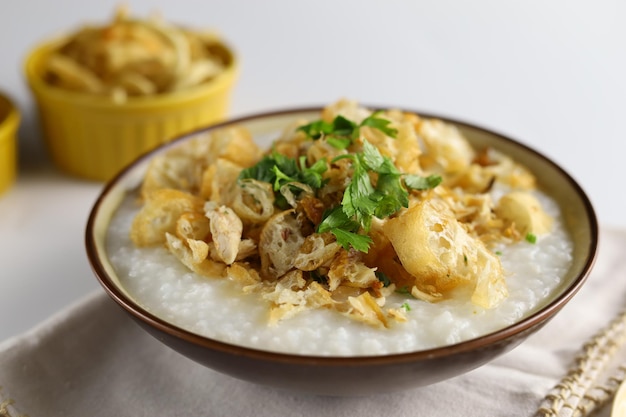 Bubur Ayam of Indonesische rijstpap met geraspte kip-kaasstick en cakwe